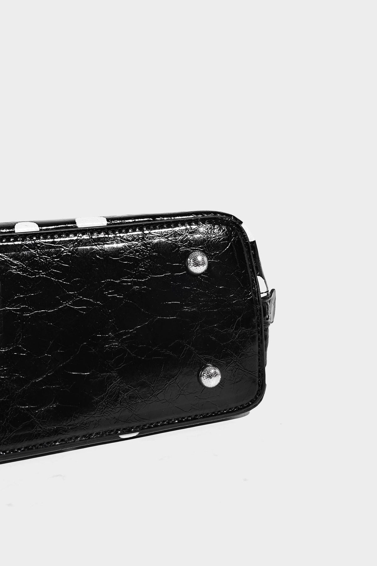 Glossy structured polka-dot satchel bag with dual top handles, silver turn-lock hardware, and detachable shoulder strap