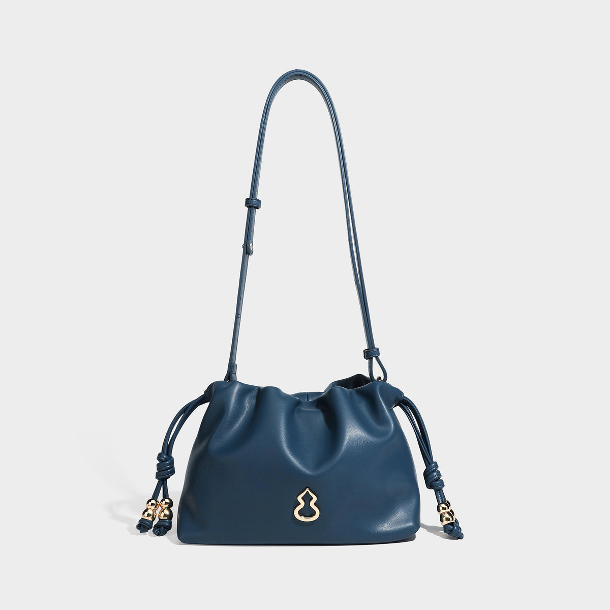 Slouchy ruched drawstring shoulder bag in smooth leather-look finish with gold-tone emblem and slim adjustable strap, detail