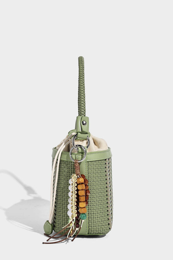 Small woven bucket bag with drawstring top, braided handle, detachable crossbody strap, and silver-tone ring hardware, detail