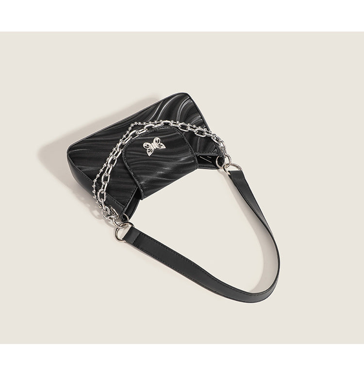 Small trapezoid shoulder bag with ripple leather-look finish, silver butterfly front clasp, and layered chain-and-ball strap