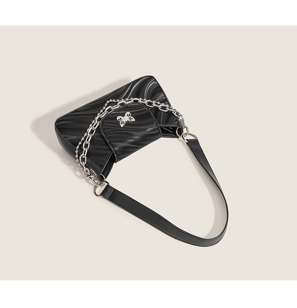 Small trapezoid shoulder bag with ripple leather-look finish, silver butterfly front clasp, and layered chain-and-ball strap