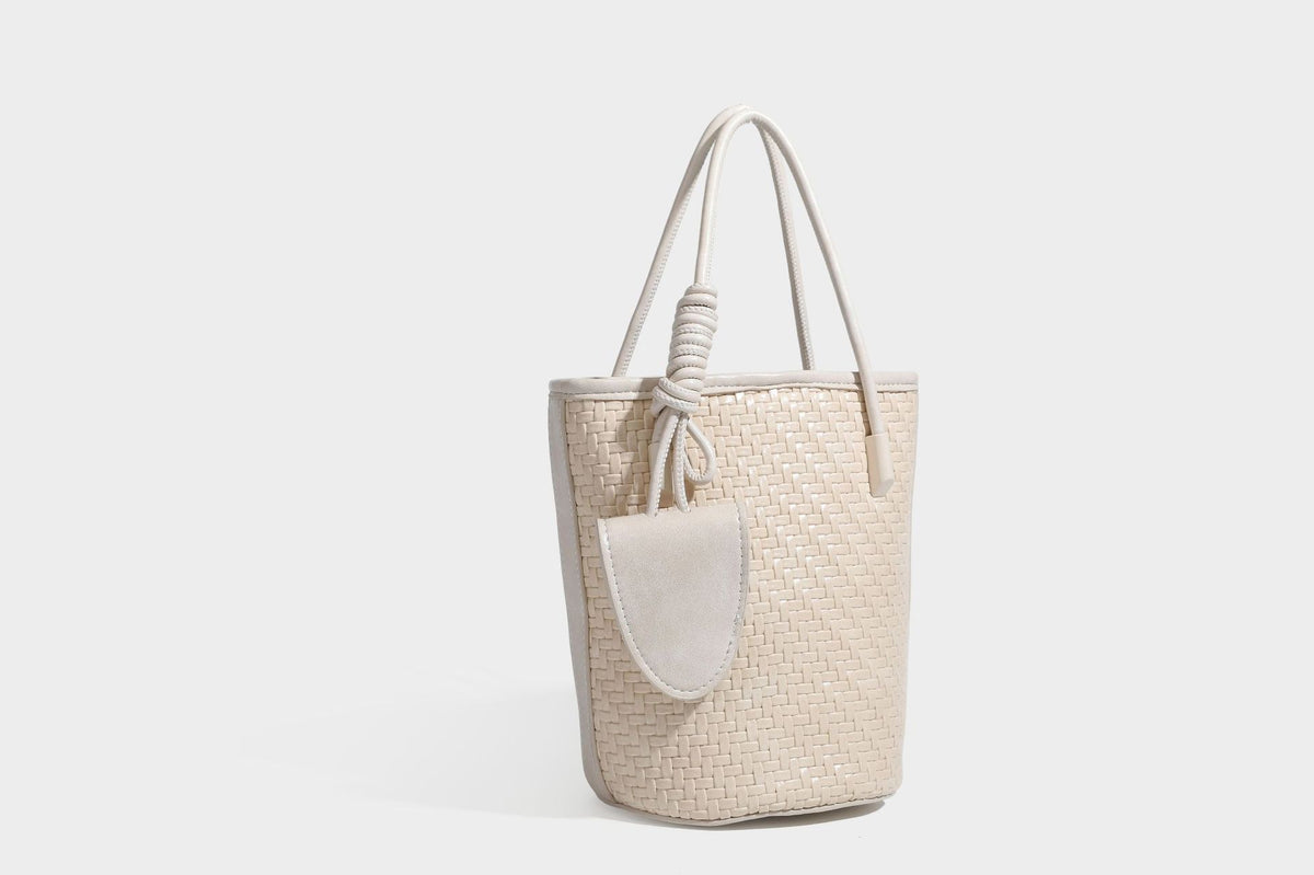 Structured woven-texture leather-look bucket bag in brown with knotted top handles, small front flap pouch, and adjustable
