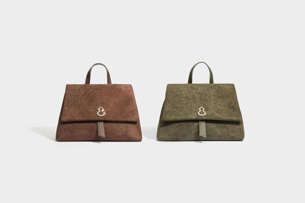 Formstabile Satchel-Tasche mit mattem Veloursleder-Finish, Überschlag, goldfarbenen Emblem-Beschlägen, kurzem Tragegriff und verstellbarem Crossbody-Riemen