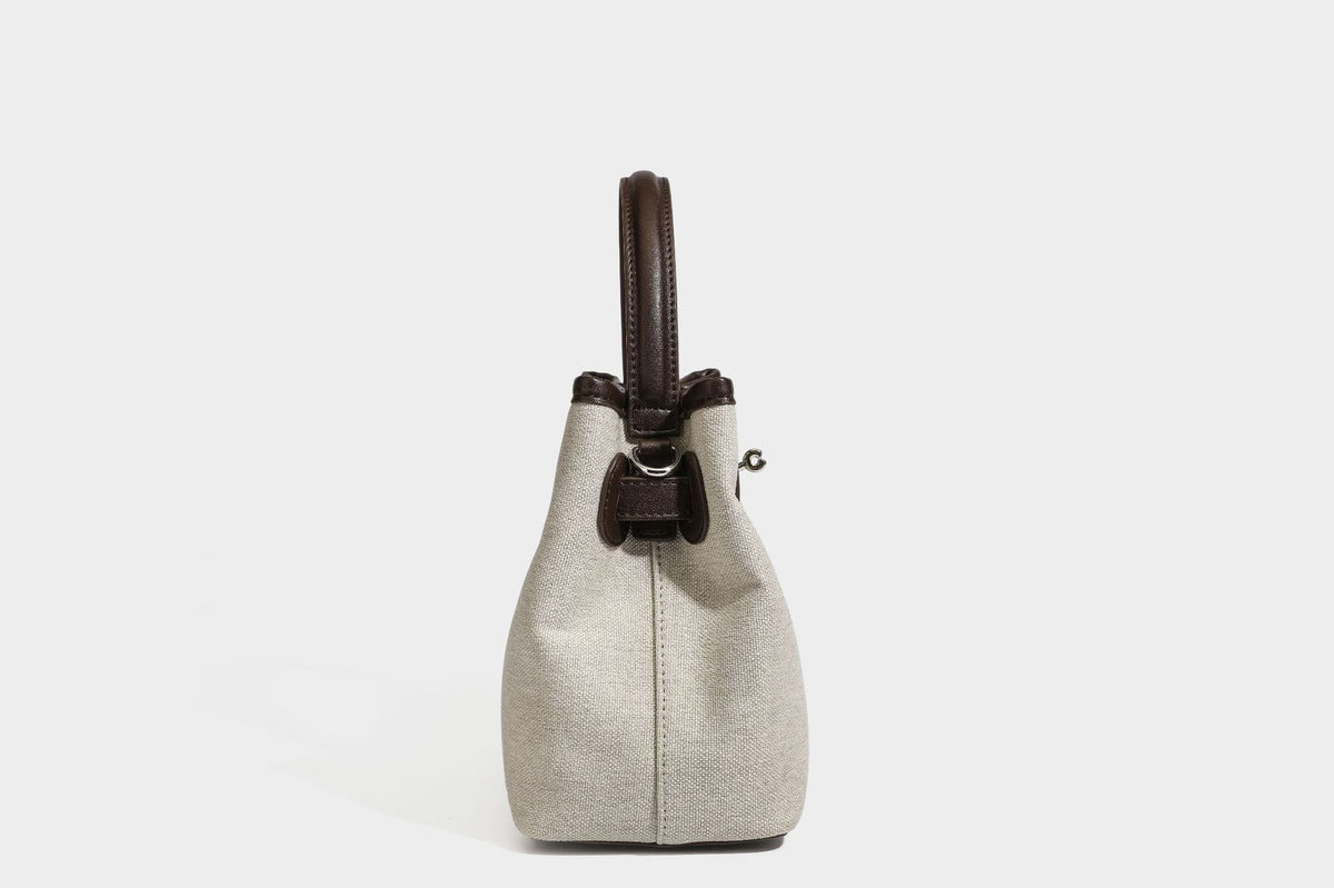 Small structured beige canvas top-handle bag with dark brown leather-look trim, silver turn-lock hardware, and detachable