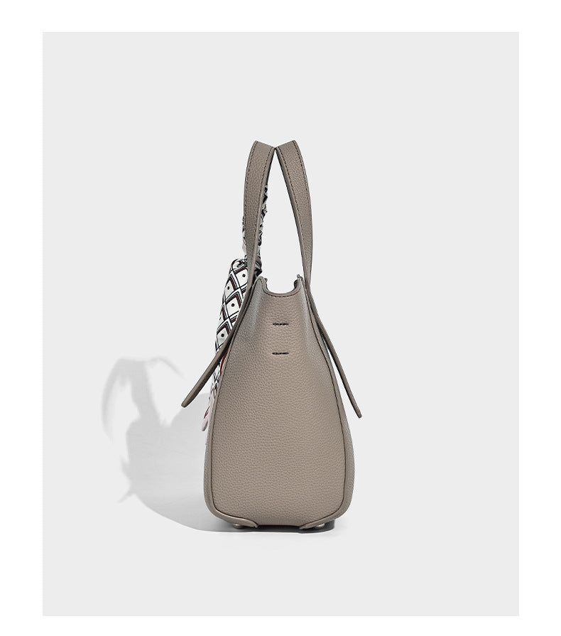 Structured pebbled leather-look tote bag with detachable scarf tie, dual top handles, and adjustable crossbody strap, detail