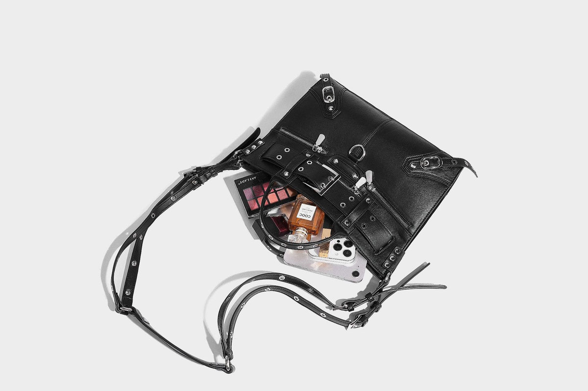 Black structured rectangular satchel bag with silver-tone rivets, large front buckle strap, zip pockets, dual top handles