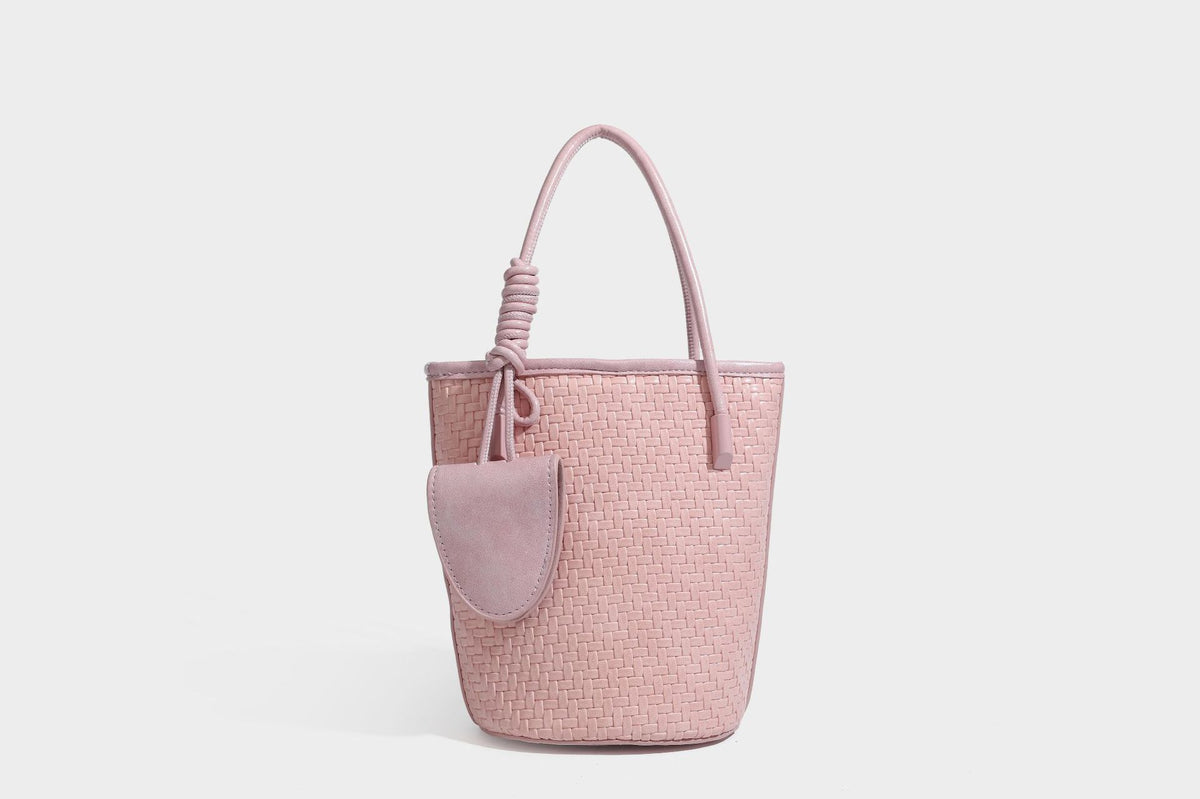 Structured woven-texture leather-look bucket bag in brown with knotted top handles, small front flap pouch, and adjustable