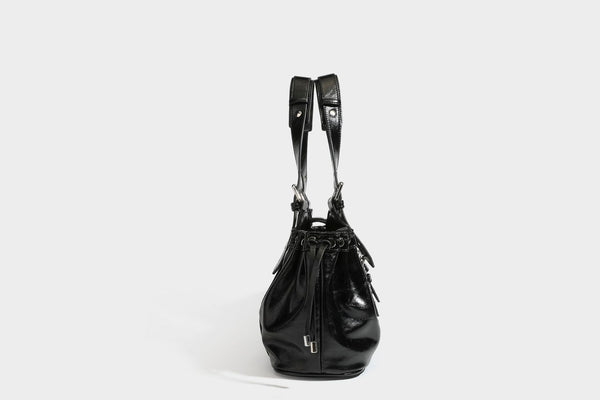 Large black glossy leather-look tote bag with silver buckle straps, eyelet grommet panels, drawstring side gathers, and