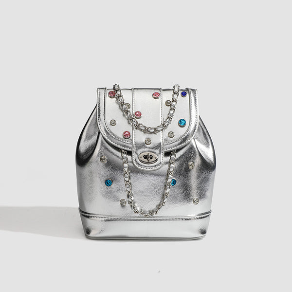 Kompakte silberfarbene Metallic-Rucksacktasche mit mehrfarbigen Kristallnieten, rundem Klappverschluss mit Drehverschluss und ineinander verflochtenem Silber