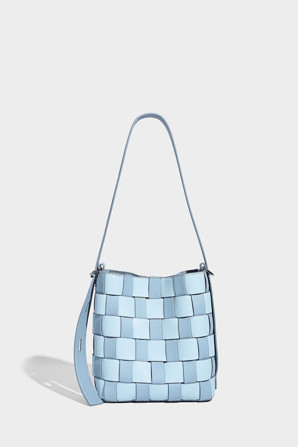 Hand-woven black-and-white checkerboard bucket bag with smooth black trim, silver-tone ring hardware, and adjustable