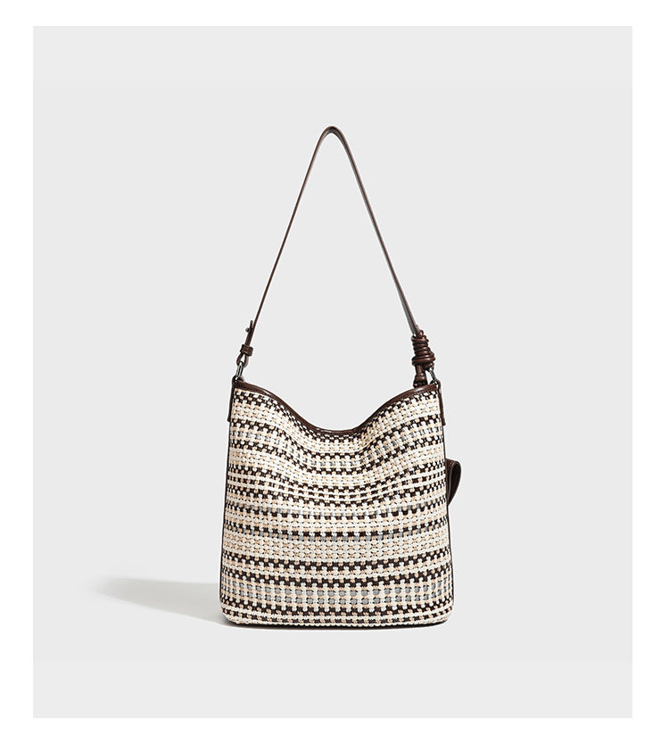 Woven stripe bucket shoulder bag in cream and dark brown with leather-look trim, knotted adjustable strap, and small shield