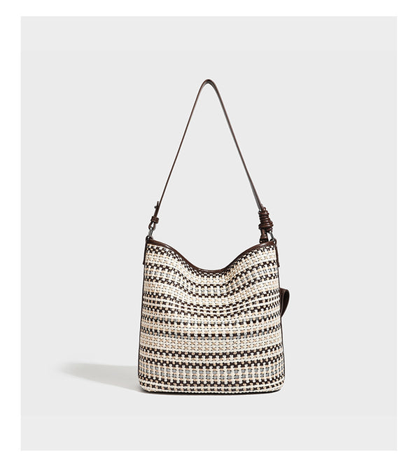 Woven stripe bucket shoulder bag in cream and dark brown with leather-look trim, knotted adjustable strap, and small shield