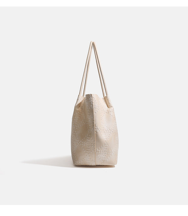 Large open-top tote bag with raised diamond-lattice stitching, long double shoulder handles, and gold-tone magnetic snap