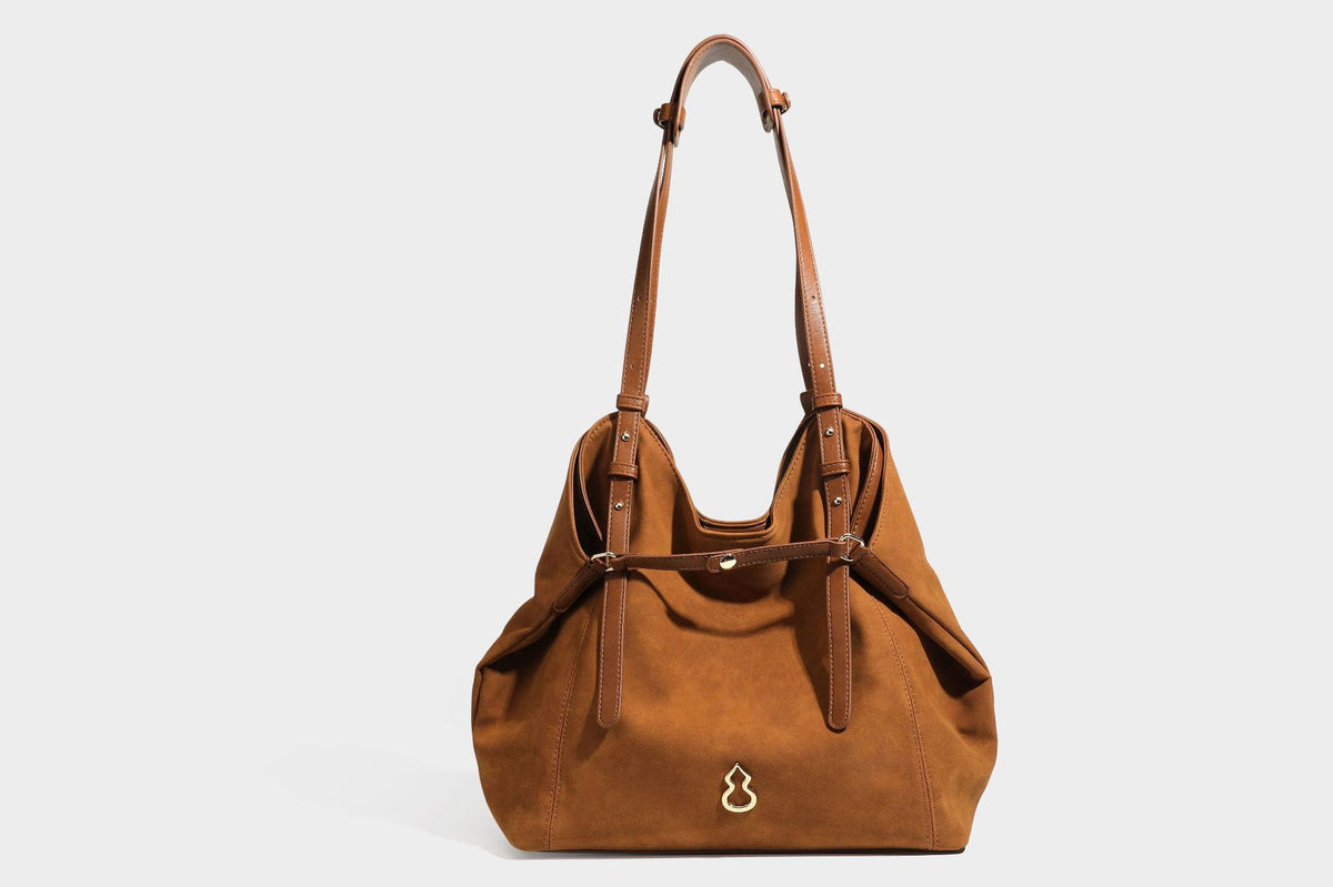 Oversized suede-finish tote shoulder bag in caramel brown with slim leather-look straps and gold-tone logo hardware, detail