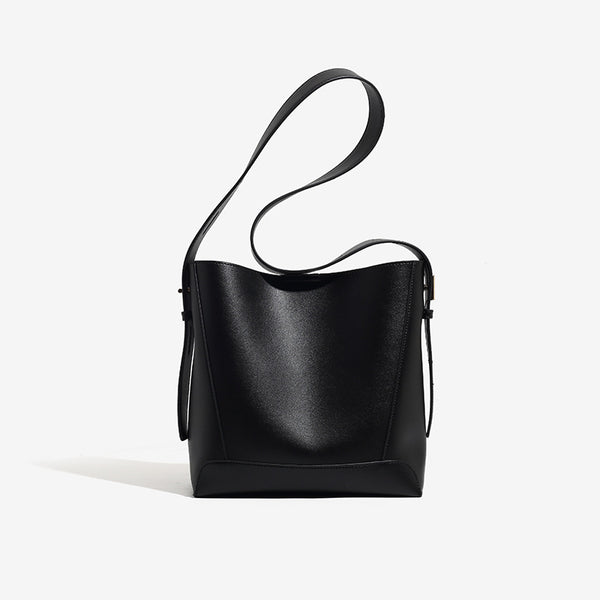 Structured smooth leather-look bucket shoulder bag with long adjustable strap and gold-tone buckle hardware in brown, detail