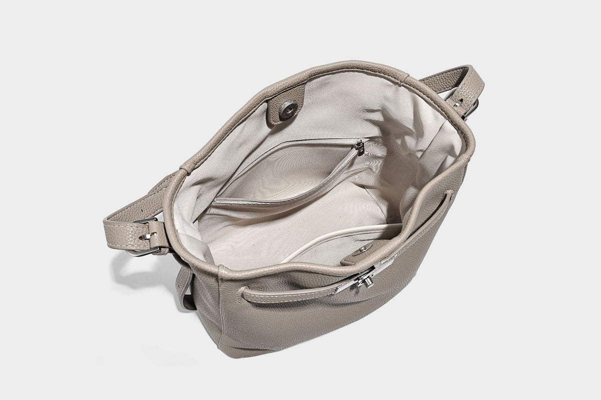 Soft-structured pebbled bucket shoulder bag with front turn-lock strap detail, adjustable strap, and hanging floral tassel