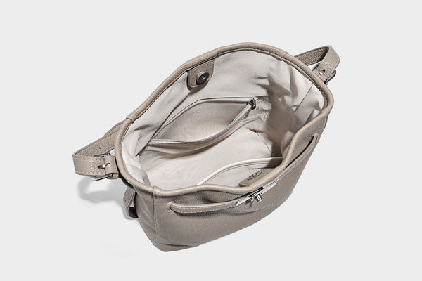 Soft-structured pebbled bucket shoulder bag with front turn-lock strap detail, adjustable strap, and hanging floral tassel