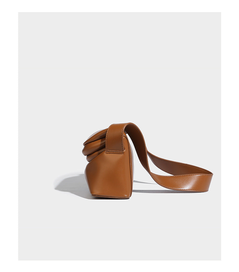 Compact structured baguette shoulder bag with smooth leather-look finish, zip top, and adjustable silver-buckle strap, detail