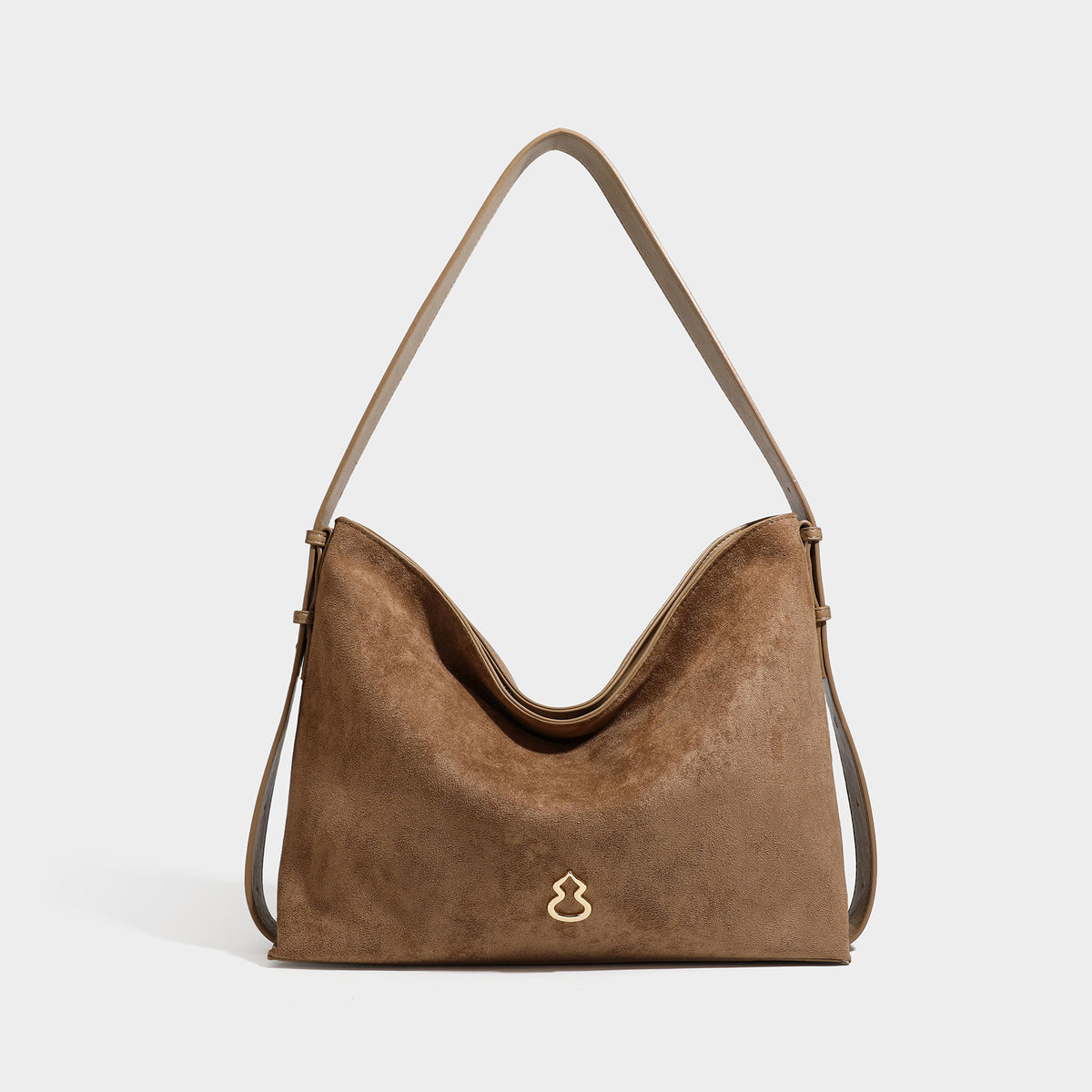 Slouchy suede-finish brown shoulder bag with long single strap and small gold-tone logo emblem on front, detail view 6