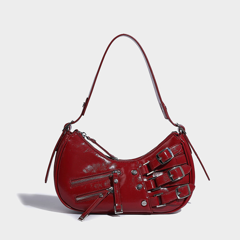 Crescent shoulder bag in washed blue denim-look PU with stacked buckle straps, front zip pocket, and silver-tone hardware