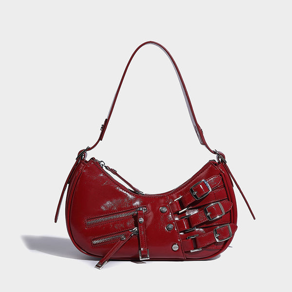 Crescent shoulder bag in washed blue denim-look PU with stacked buckle straps, front zip pocket, and silver-tone hardware