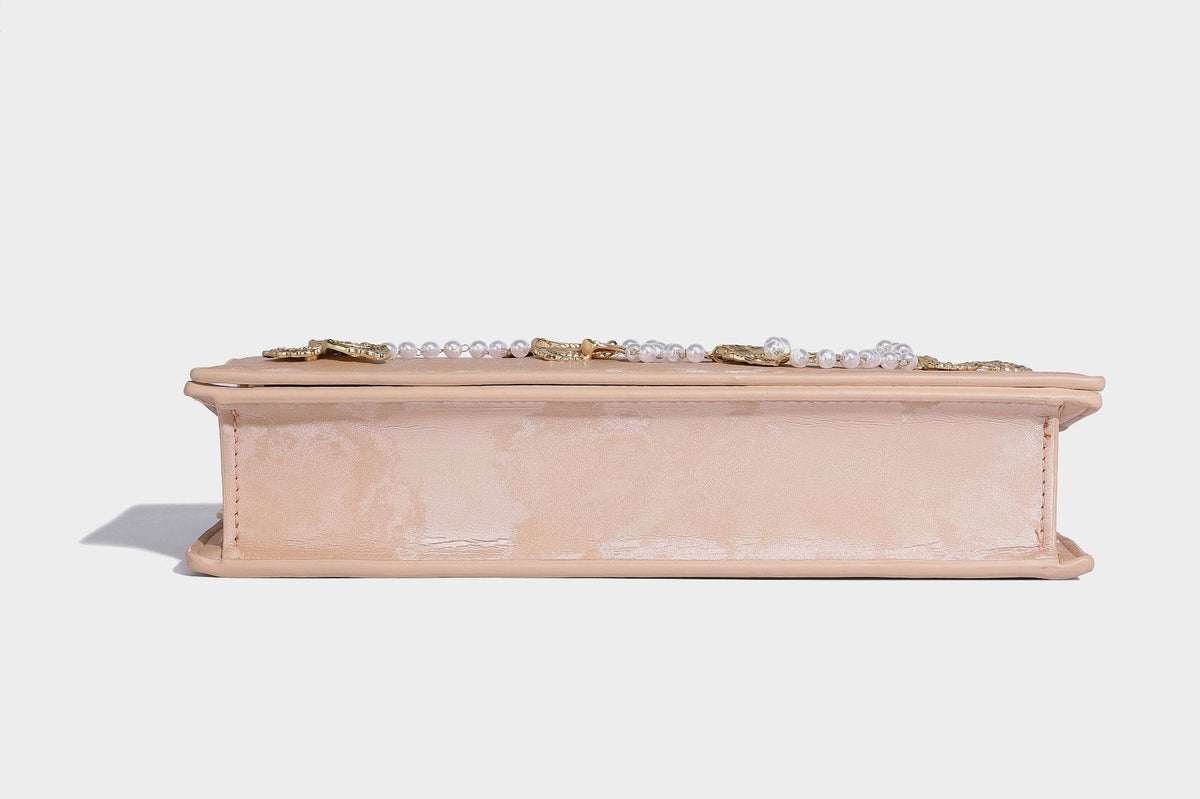 Formstabile rechteckige Umhängetasche mit Überschlag, goldfarbenen Schmetterlingsanhängern und Perlenstrang-Verzierung an einer goldfarbenen Kette