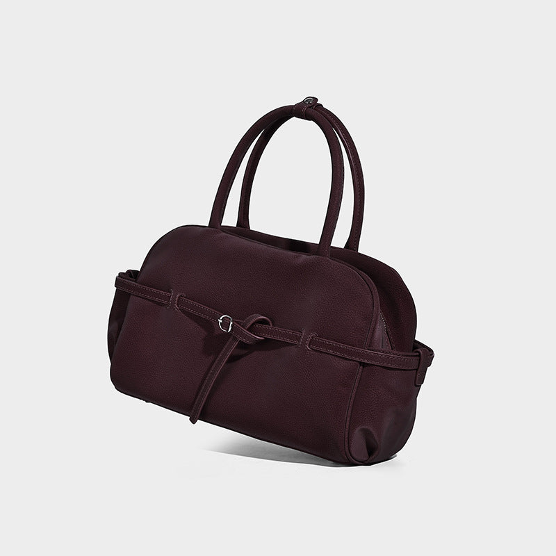Strukturierte Henkeltasche mit matter, genarbter Oberfläche, umlaufendem Riemen mit Ringbeschlägen, zwei Tragegriffen und abnehmbarem Umhängeriemen