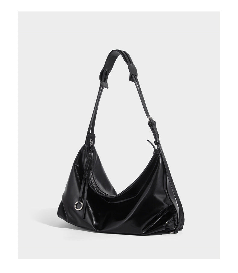 Glossy black slouchy hobo shoulder bag with zip closure, silver-tone ring hardware, and adjustable crossbody strap, detail