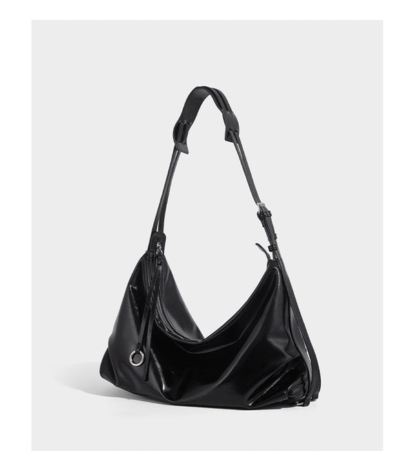 Glossy black slouchy hobo shoulder bag with zip closure, silver-tone ring hardware, and adjustable crossbody strap, detail