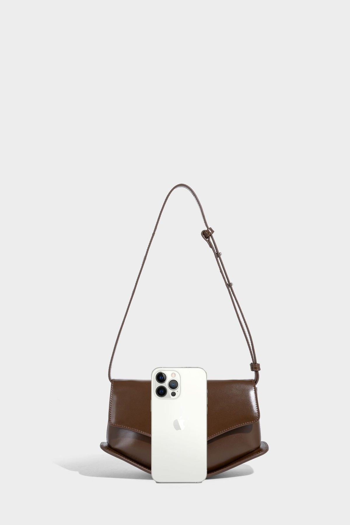 Small structured saddle bag with glossy leather-look finish, angular flap front, silver-tone metal clasp, and slim