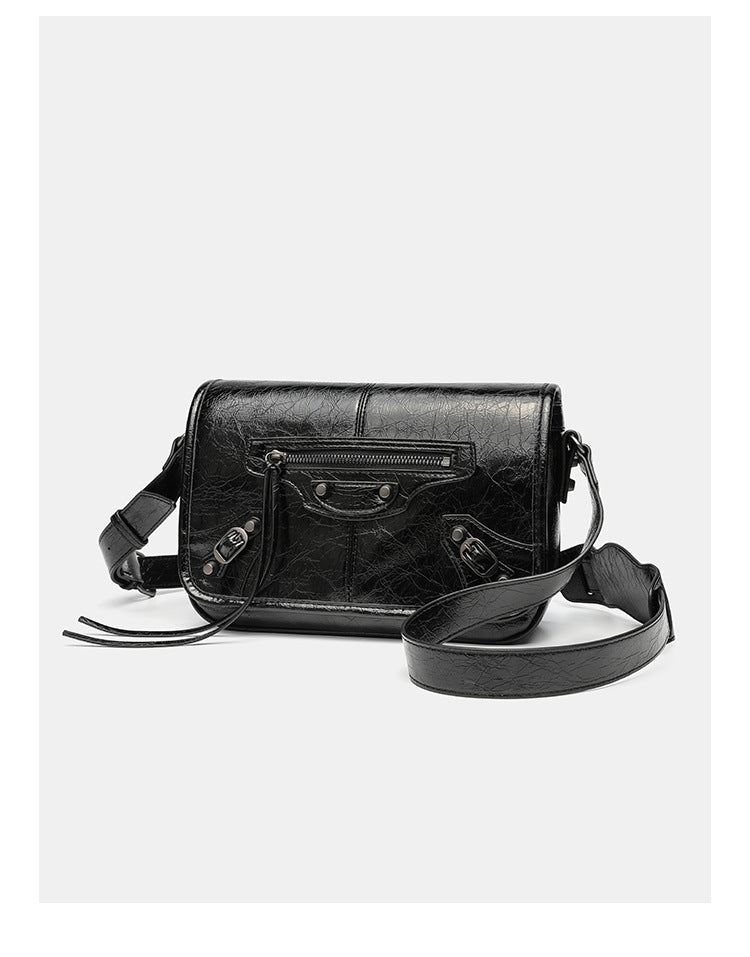 Small structured rectangular crossbody bag with crinkle leather-look finish, front zip pocket, gunmetal stud hardware, and