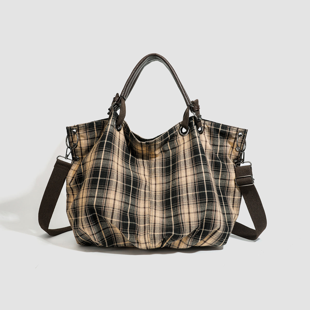 Slouchy matte canvas tote bag with dark dual top handles, metal grommet hardware, and detachable long shoulder strap, detail