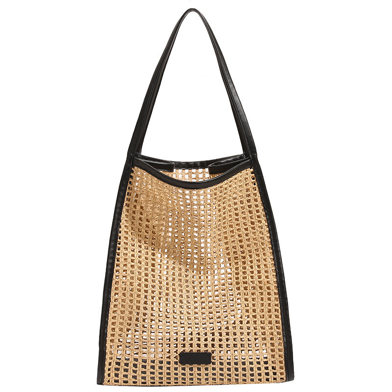 Tan open-weave raffia tote bag with black leather-look trim and long black shoulder straps, trapezoid silhouette, detail view