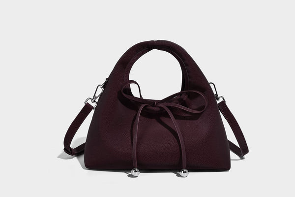 Pebbled matte trapezoid top-handle bag with drawstring bow closure, bead-tipped cords, silver-tone hardware, and detachable