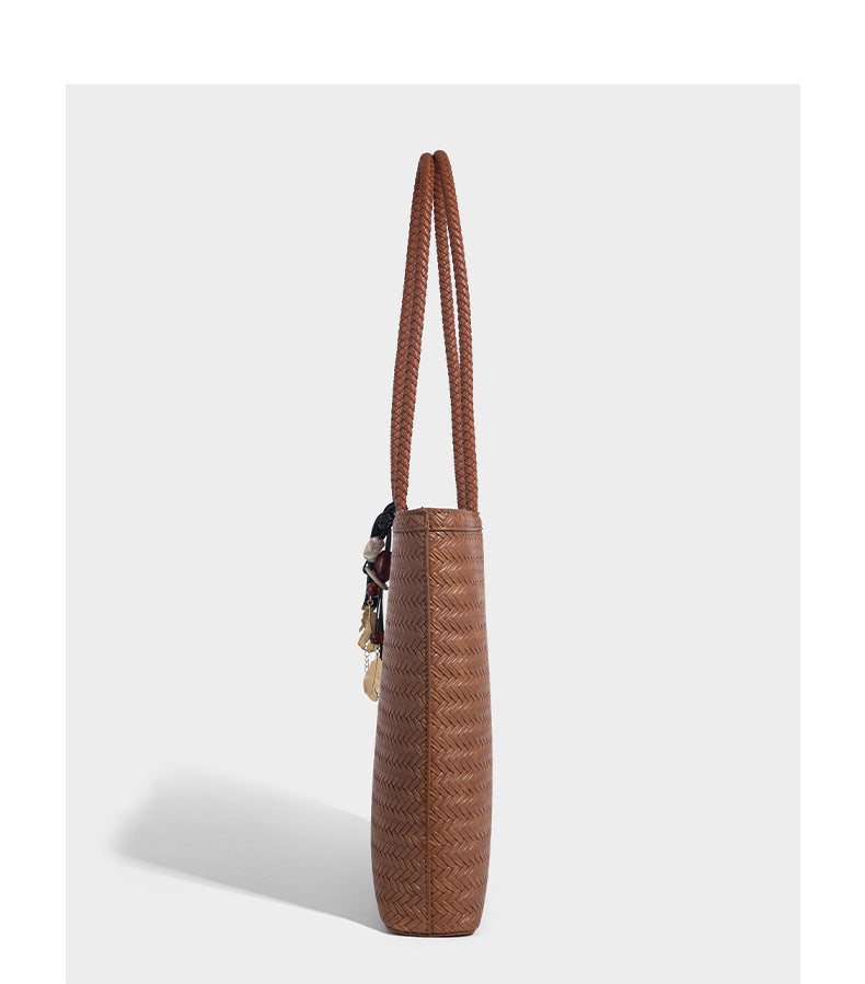 Structured woven herringbone tote bag with braided double shoulder handles in tan brown, shown with matching drawstring