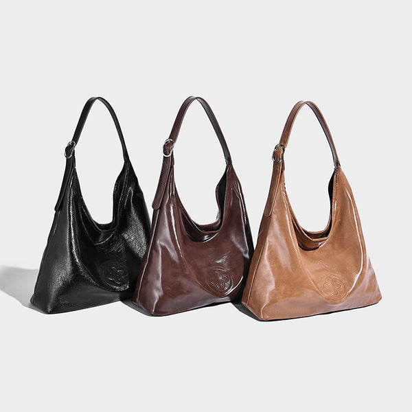 Glossy slouchy hobo shoulder bag with adjustable strap and embossed floral emblem, detail view 2