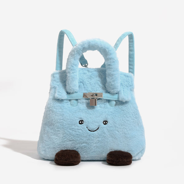 Ice-blue plush faux-fur Kelly-style convertible bag with embroidered smiling face, dark pom-pom feet, silver-tone clasp
