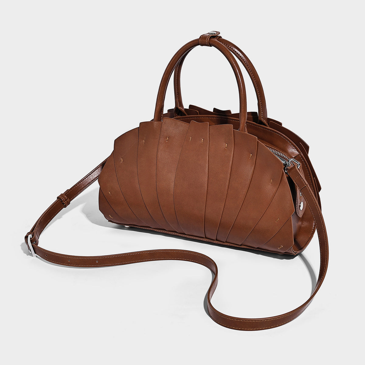 Structured dome satchel with fan-pleated leather-look exterior, dual top handles, and detachable shoulder strap, detail view