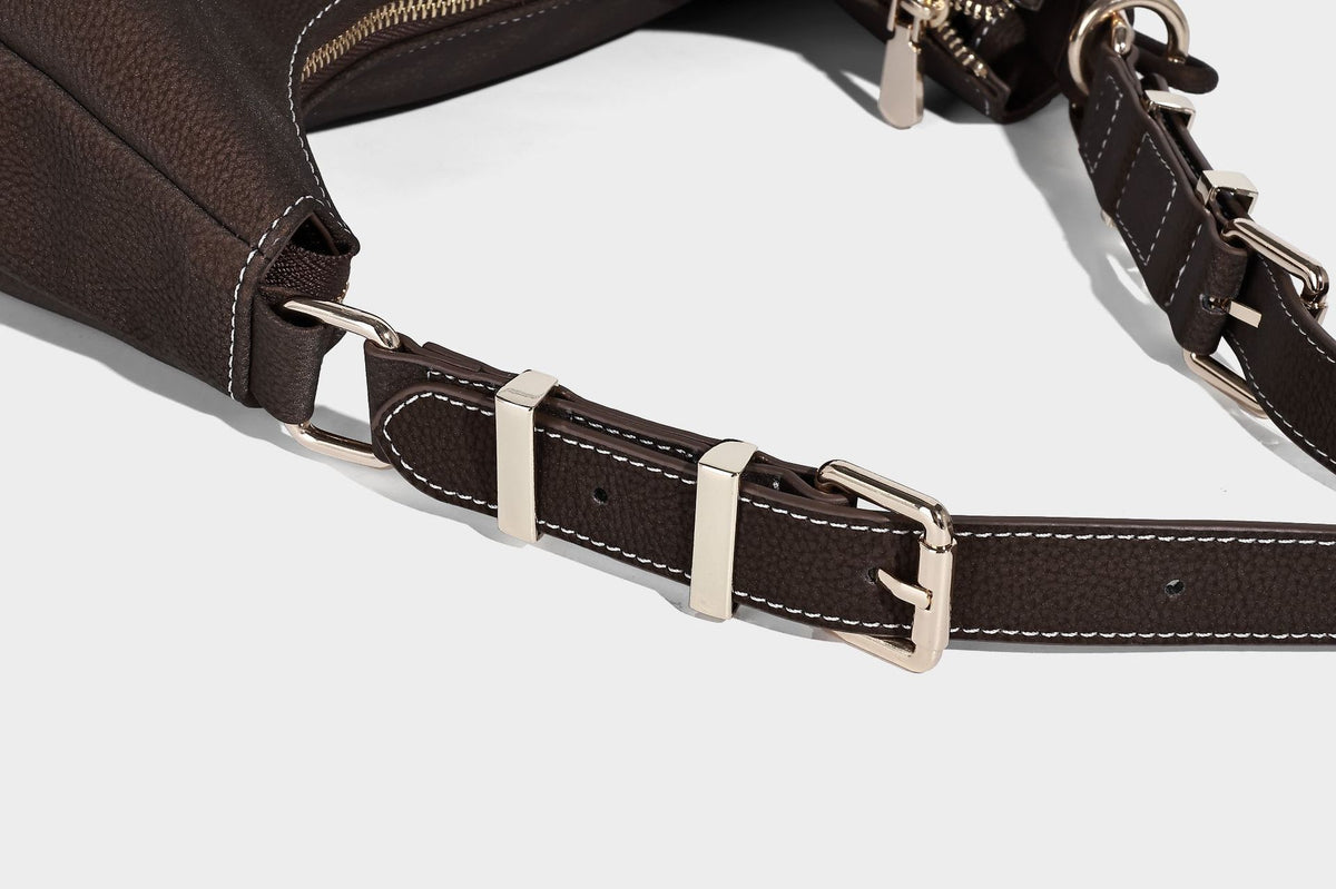 Crescent hobo shoulder bag in pebbled leather-look finish with top zipper, adjustable strap, gold-tone ring hardware, and