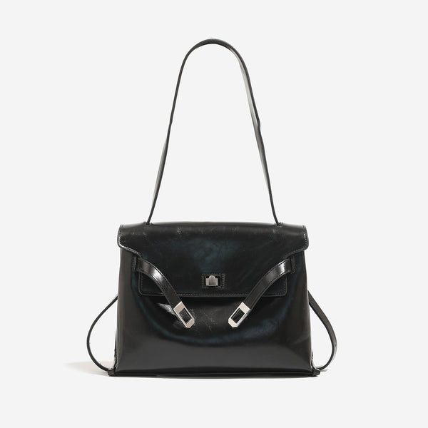 Structured trapezoidal flap satchel bag with silver-tone turn-lock clasp, decorative front strap tabs, gusseted sides, and