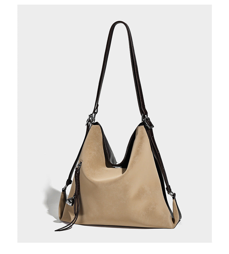 Slouchy hobo tote bag with matte leather-look finish, triangular silhouette, front zip pocket, and adjustable shoulder strap