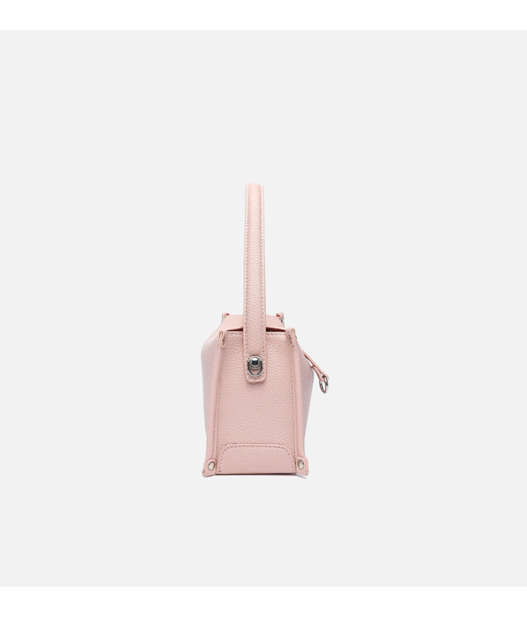 Small structured pebbled-finish convertible bag with silver corner studs, zip top, and detachable shoulder strap, detail view