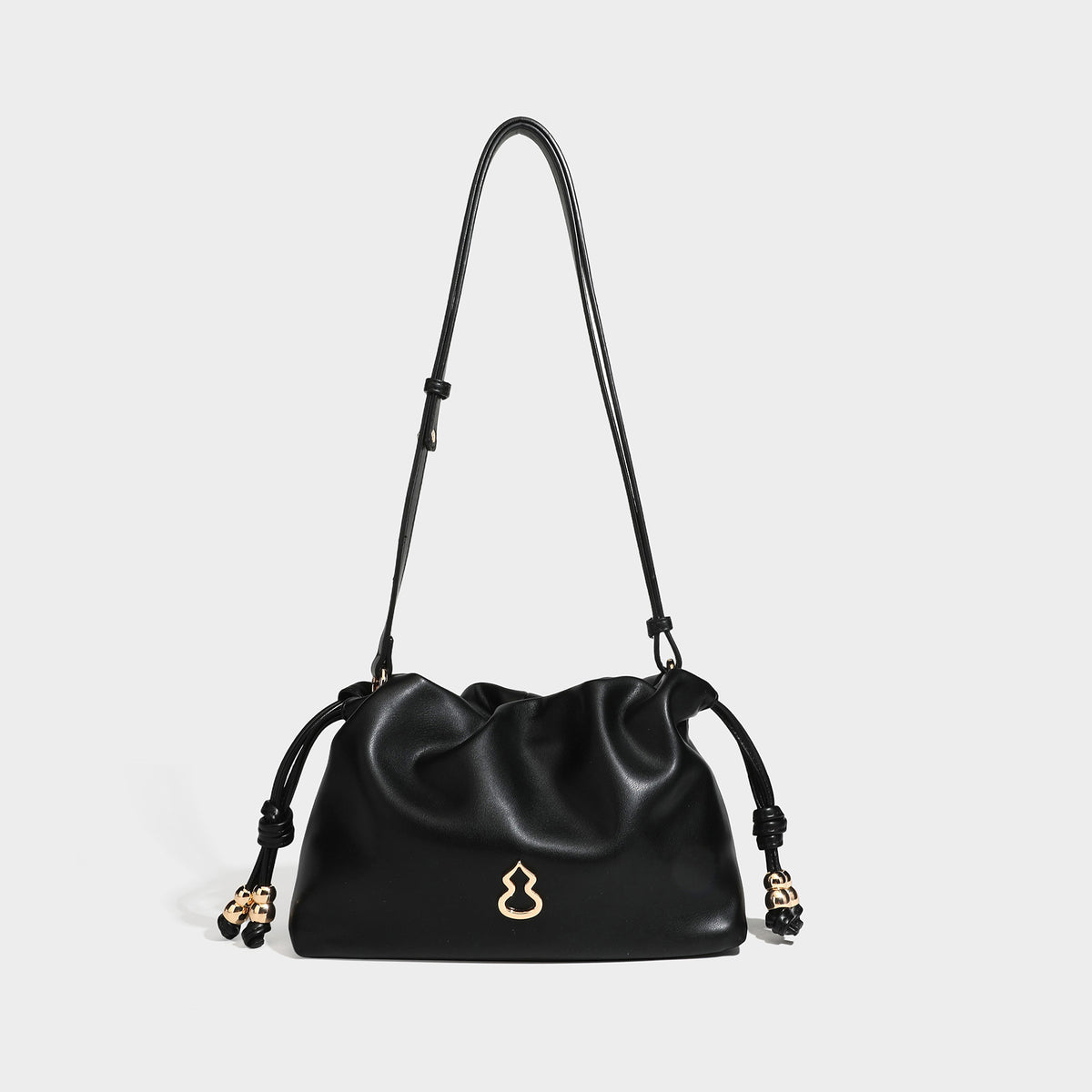 Slouchy ruched drawstring shoulder bag in smooth leather-look finish with gold-tone emblem and slim adjustable strap, detail
