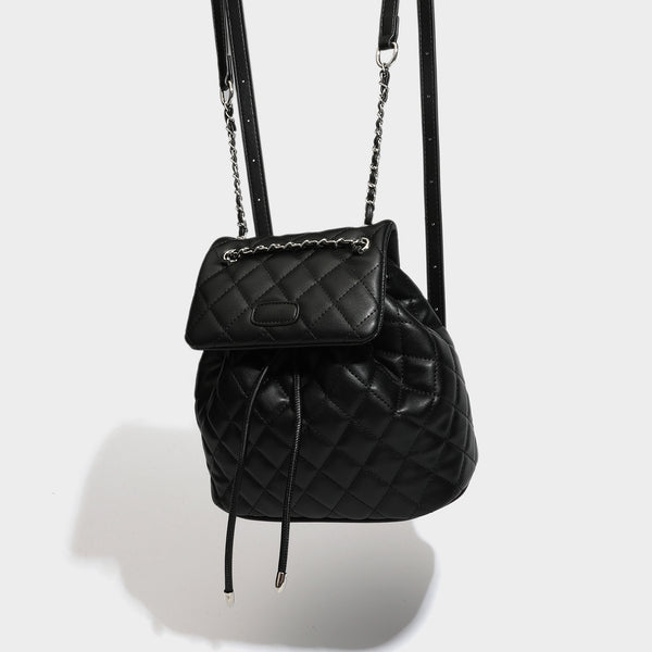 Black diamond-quilted backpack handbag with silver-tone chain flap accent and adjustable shoulder straps, detail view 2