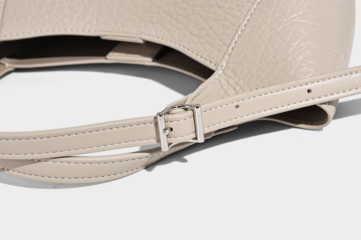 Small pebbled half-moon shoulder bag with dual top handles, detachable crossbody strap, and silver-tone hardware, detail view