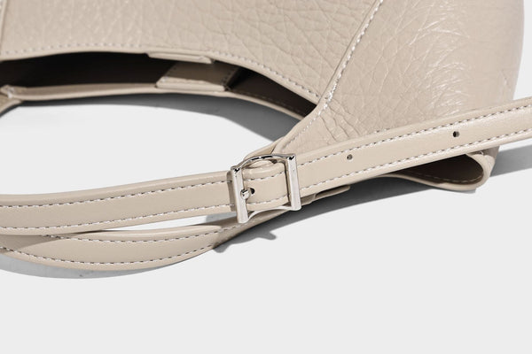 Small pebbled half-moon shoulder bag with dual top handles, detachable crossbody strap, and silver-tone hardware, detail view