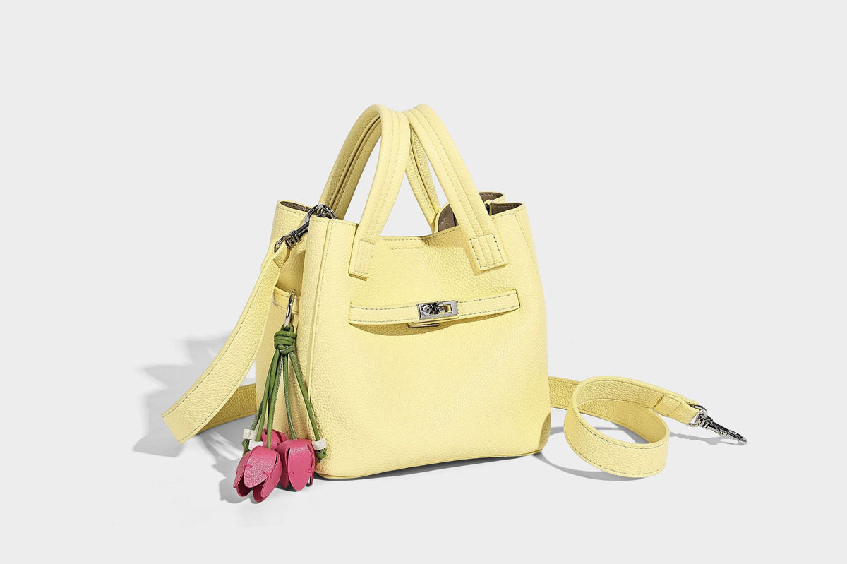 Small structured pebbled bucket tote bag with dual top handles, silver turn-lock front pocket, and detachable shoulder strap