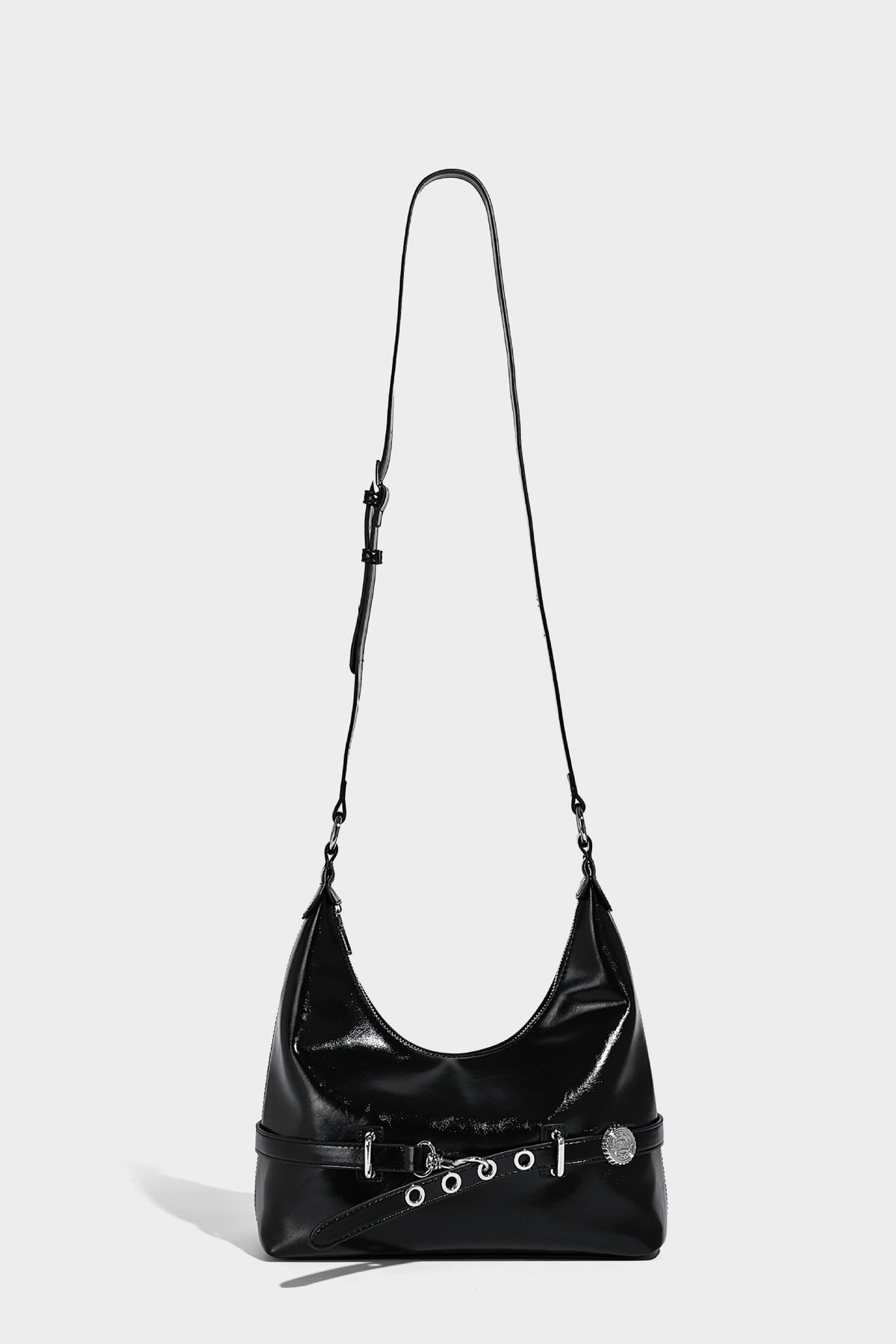 Glossy black slouchy hobo shoulder bag with silver-tone hardware, belt-style grommet strap at base, and long adjustable