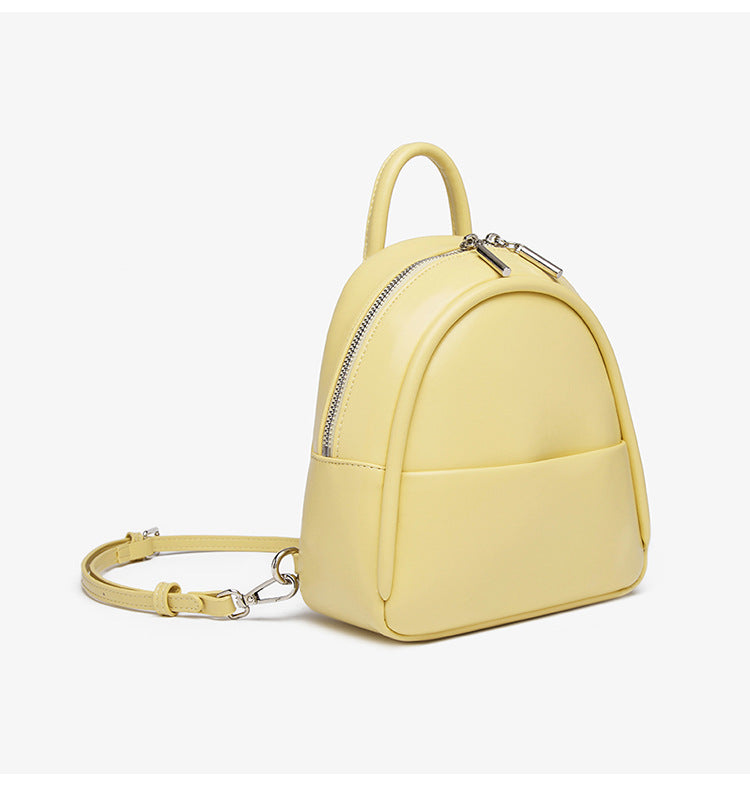 Kleine kuppelförmige Mini-Rucksackhandtasche in Pastellgelb mit glatter Lederoptik, oberem Bogenreißverschluss und silberfarbenen Details, Detailansicht