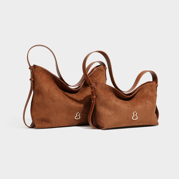 Slouchy suede-finish brown shoulder bag with long single strap and small gold-tone logo emblem on front, detail view 45